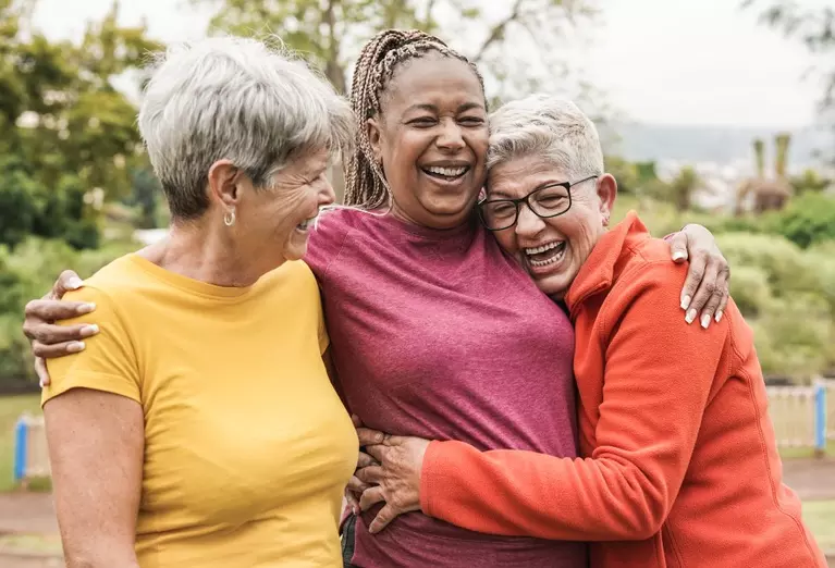 Three women laughing and embracing each other